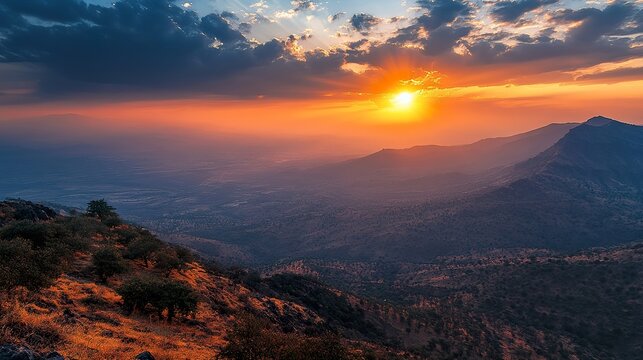 A dramatic sunset casting fiery hues over the Girnar Hills, highlighting the contours of the landscape and the tranquility of nature.