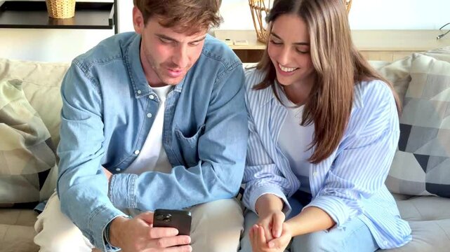 Couple sitting together on the couch, viewing vacation photos on their phone, reliving memories from beach and mountain trips, sharing smiles while reminiscing about their travels.