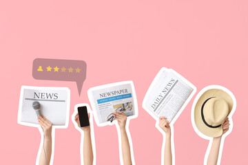 Female hands with newspapers, hat, microphone and mobile phone on pink background