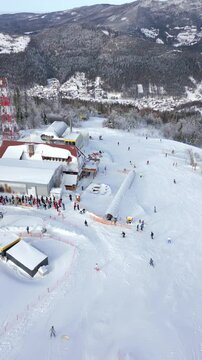 Aerial view of a queue of people waiting for a chairlift at a snowy ski slope in a winter resort
