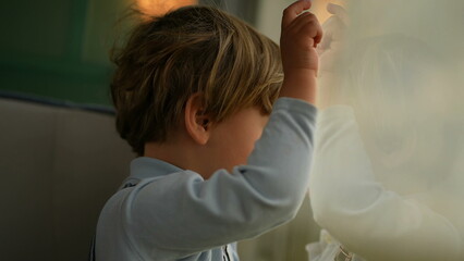 One year old toddler leaning on train window looking at landscape passing by