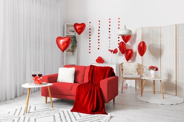 Interior of light living room with red sofa and balloons for Valentine's Day