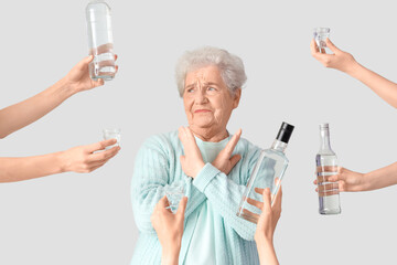Senior woman rejecting vodka on light background