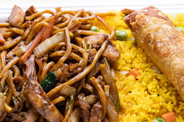 Chinese delivery menu food. Lo mein noodles, an egg roll over scoop of yellow fried rice.