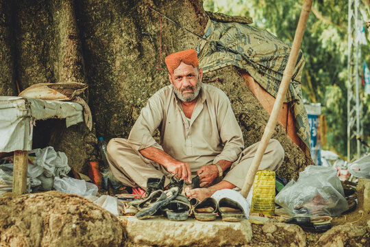 Poor old Indian shoe man cobbler repairing shoes in his road side shop