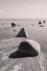 Minimalistic black and white rocks and breakwater in the sea