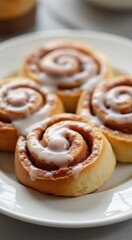 Four cinnamon rolls on a plate with icing on them