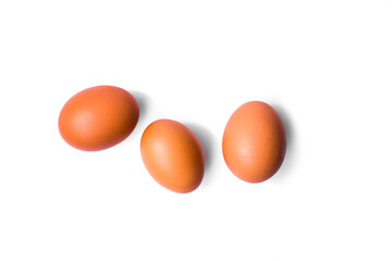 three brown chicken eggs on a white background