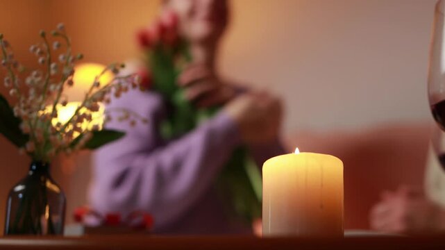 Romantic surprise: a man gives a bouquet of red tulips to a woman during a romantic date by candlelight.International women's day