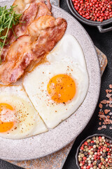 A hearty breakfast with fried eggs, bacon, tomatoes, microgreens