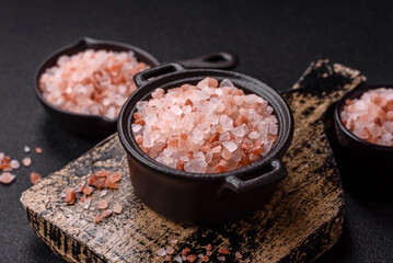 Pink himalayan salt in a black bowl on a dark concrete background