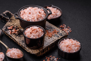Pink himalayan salt in a black bowl on a dark concrete background