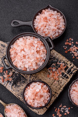 Pink himalayan salt in a black bowl on a dark concrete background