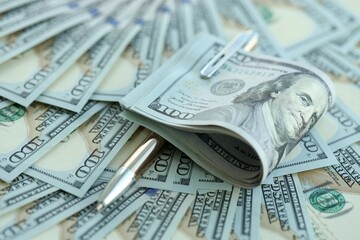 Golden pen clipping big amount of hundred dollar bills US banknotes