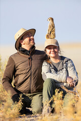 Couple with meerkat on safari.