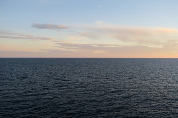 Die Sonne geht unter über dem Skagerrak an einem Sommerabend. Das Meer ist ruhig, und über dem Horizont sind ein paar Wolken zu sehen. Gesehen von Bord einer Fähre von Oslo nach Kopenhagen.