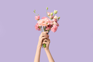 Female hands with beautiful bouquet of flowers on purple background