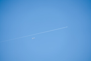 Airbus A380 and a twin engined jet liner aircraft in deep blue sky, contrails vapour trails