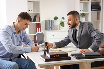 Male lawyer with client in wheelchair signing document at office