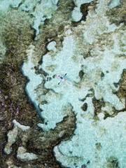 Woman kayaking over coral reefs.
