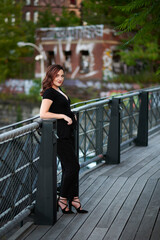 Stunning young woman poses for photo wearing black jumper on elevated walking trail