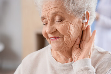 Senior woman with hearing aid at home, closeup