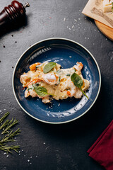 Creamy seafood pasta with shrimp and spinach in a rich sauce, served on a stylish blue plate