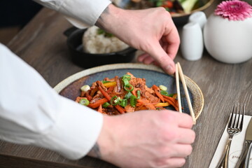A vibrant and spicy Korean-style dish featuring tender pork, fresh vegetables, and steamed rice, beautifully plated in a restaurant setting.