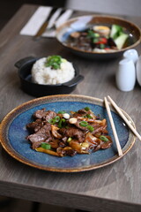 A close-up shot of a traditional Korean dish, Bulgogi, served in a rustic restaurant setting.