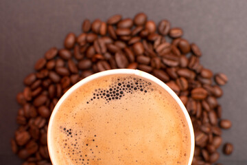 Paper cup with coffee on roasted coffee beans	