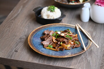 A close-up shot of a traditional Korean dish, Bulgogi, served in a rustic restaurant setting.