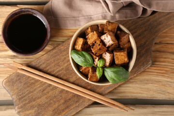 Bowl with pieces of fried tofu cheese and basil on wooden background