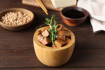 Bowl with pieces of fried tofu cheese and micro green on wooden background