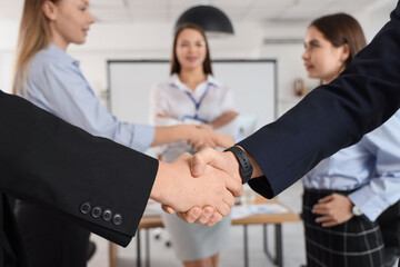 Business men shaking hands after negotiations in conference hall, closeup