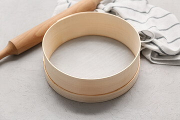 Wooden sieve for flour, rolling pin and napkin on grunge background