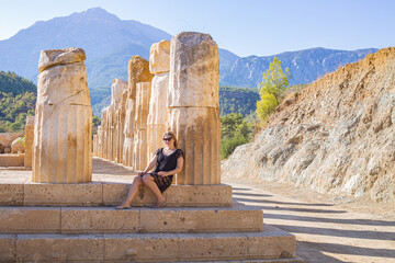 girl sitting at the base of antique columns