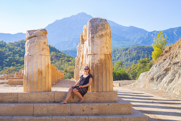 girl sitting at the base of antique columns