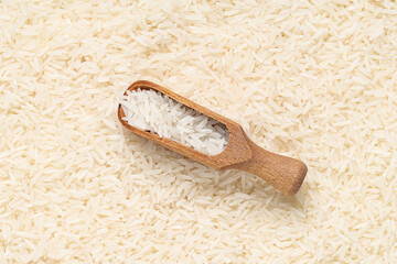 Closeup view of wooden scoop and raw rice as background, closeup