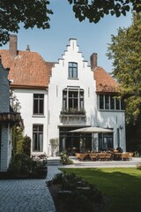 Elegant white house with a spacious patio in a serene garden setting, showcasing a blend of modern comforts and classic architecture under clear blue skies