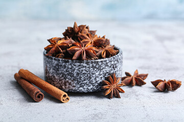 Bowl with anise stars and cinnamon on grey table