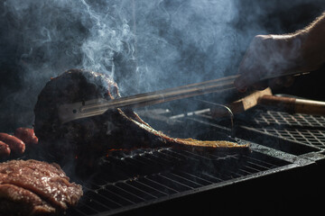 Beef steak on the grill with smoke and flames.