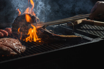 Beef steak on the grill with smoke and flames.