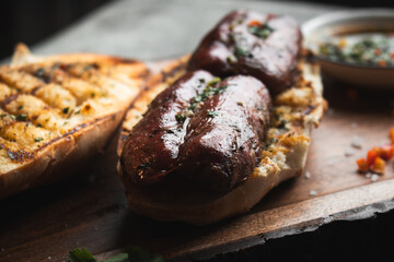A choripan with chimichurri sauce on a wooden board. Traditional argentinian sandwich. 