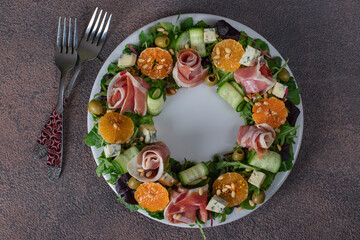 Wreath-shaped salad with jamon, tangerines, arugula, dor bleu cheese, cucumber and pine nuts