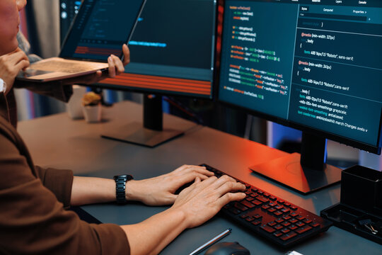 Serious of IT developers discussing intelligent website development coder system running data online two screens with laptop showing information network at neon light room at modern office. Infobahn.