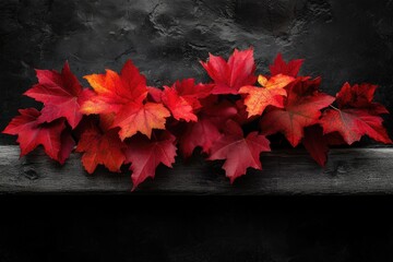 Vibrant red maple leaves arranged on a dark wooden surface, creating an autumnal scene.