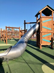 New empty playground in the sunny day with long shadows. Long tunnel slide and rope ladders.