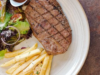 A plate of steak and fries with a side of salad