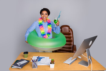 Energetic businesswoman ready for summer vacation with lei and drink at office desk