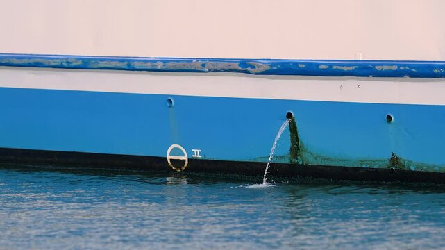 Bilge water being pumped out of a blue ship